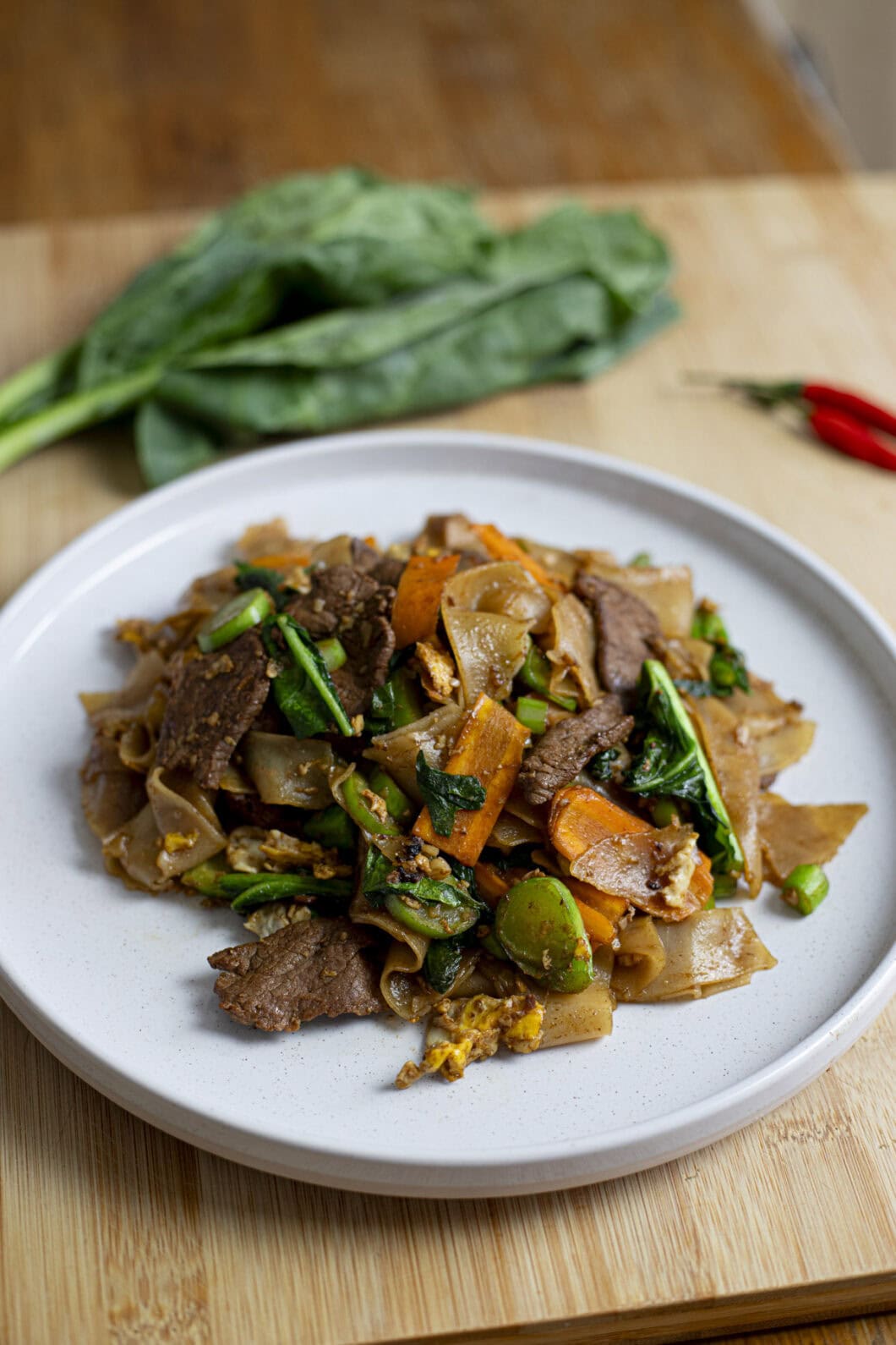 Pad See Ew, fresh wide rice noodles with a soy based sauce, carrots and Chinese broccoli (Gai Lan)