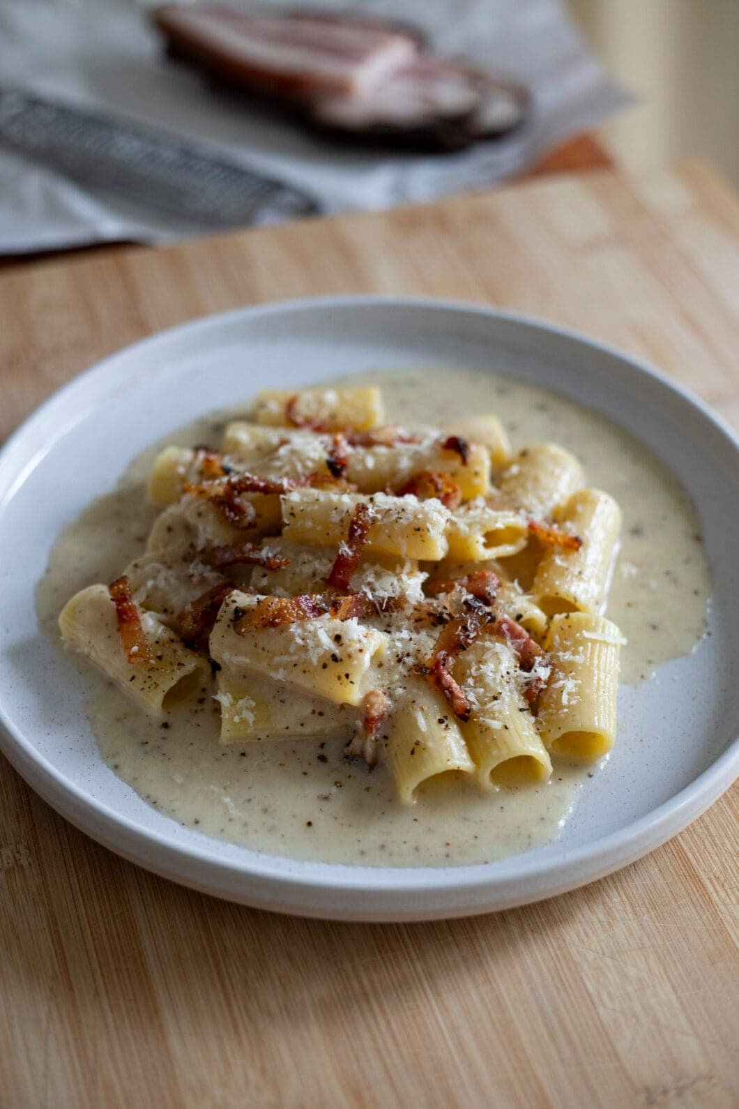 Rigatoni alla Gricia in a white plate with guanciale and Pecorino romano
