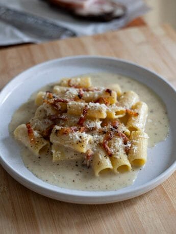 Rigatoni alla Gricia in a white plate with guanciale and Pecorino romano