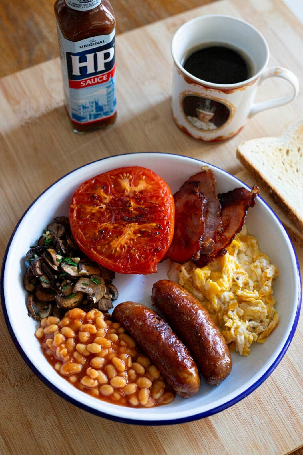 English breakfast with sausage, bacon, egg, beans, mushrooms and grilled tomato