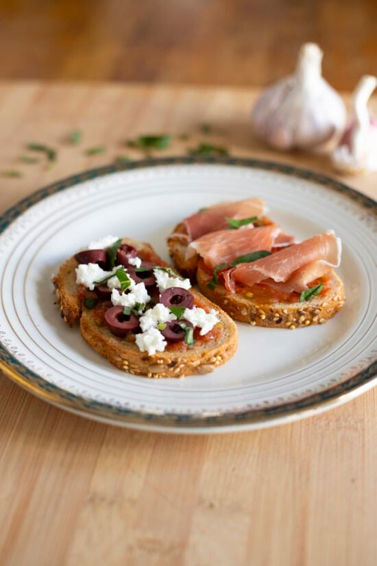 Pan con tomate two ways - one with feta cheese and slices kalamata olives, one with cured ham