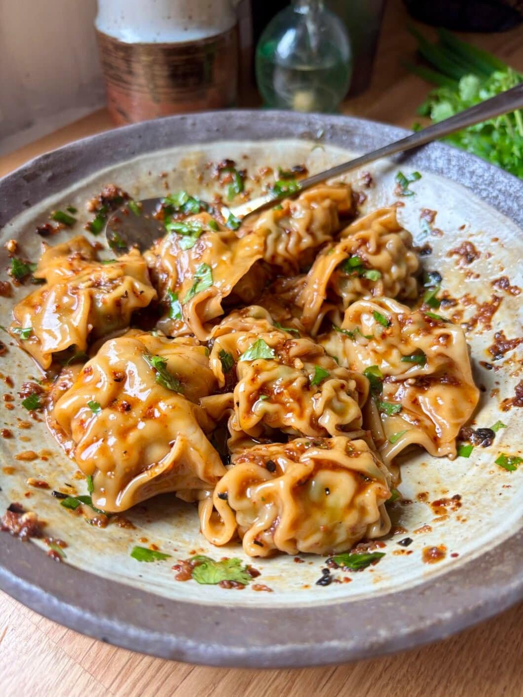 Glossy chili oil wontons coated in vibrant red chili oil, shiny, spicy and incredibly appetizing.