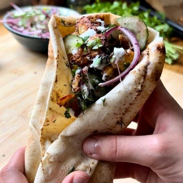 Grilled halloumi pita sandwiches with crispy cheese, fresh vegetables and creamy sauce in warm flatbread, an easy Mediterranean vegetarian lunch idea.