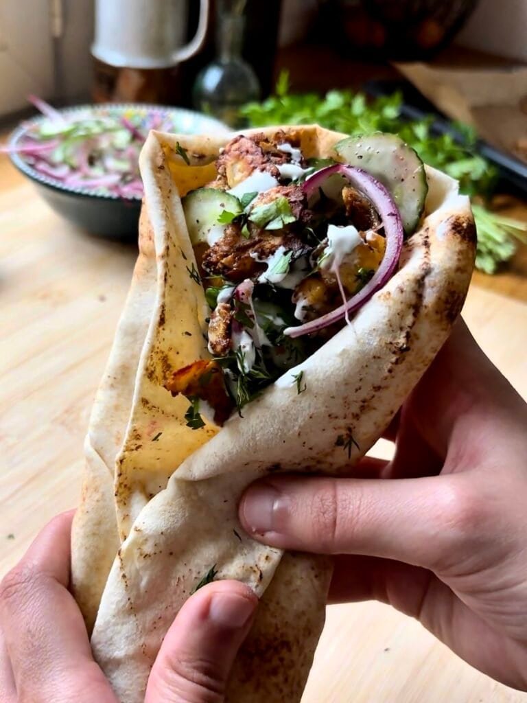 Grilled halloumi pita sandwiches with crispy cheese, fresh vegetables and creamy sauce in warm flatbread, an easy Mediterranean vegetarian lunch idea.