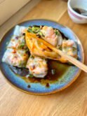Close-up of glossy shrimp rice rolls drizzled with sweet soy sauce & scallions