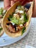 Corn taco with juicy grilled chicken thighs, salsa verde, onion and cilantro