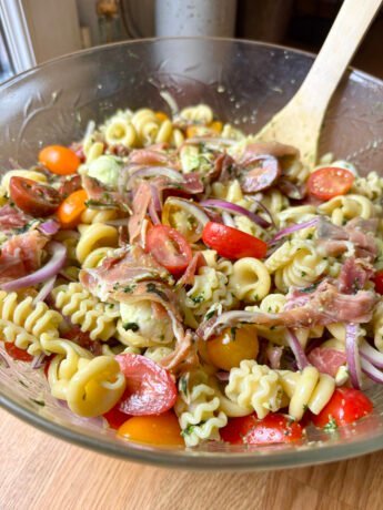 Pesto pasta salad with tomatoes, cured ham, red onions and mini mozzarella balls