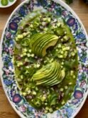 large oval dish filled with aguachile -raw shrimps, a green marinade with cucumber and fresh green chilies plus cubed cucumber onion cilantro and sliced green chilies and avocado slices