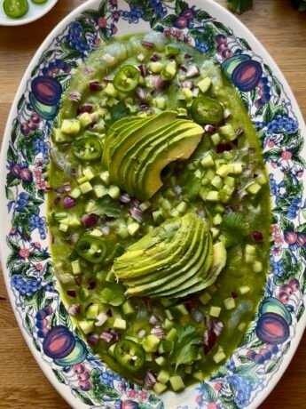 large oval dish filled with aguachile -raw shrimps, a green marinade with cucumber and fresh green chilies plus cubed cucumber onion cilantro and sliced green chilies and avocado slices