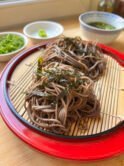 Japanese bamboo plate with two soba noodles nest, a dipping sauce bowl with mentsuyu and water, scallions and wasabi on the side