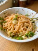 Shiny rice noodles with fishballs and green onion, coated in a luscious reddish sauce