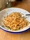 Rice noodles coated in a shiny, garlicky and spicy semi-transparent sauce, topped with scallions