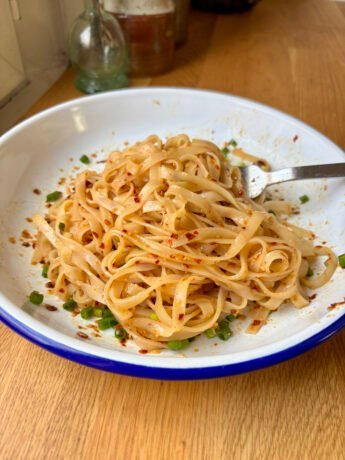 Rice noodles coated in a shiny, garlicky and spicy semi-transparent sauce, topped with scallions