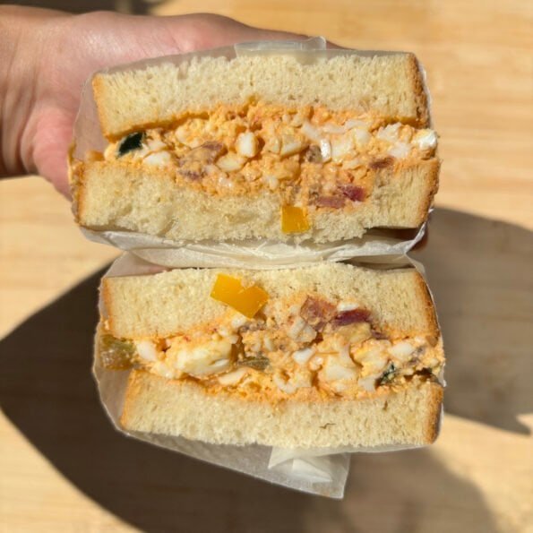 Thick sandwich bread filled with a creamy egg salad that comprises tomatoes, bacon and chilies