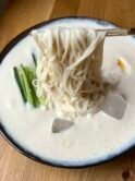 Milky white noodle soup with thin somen noodles, thin cucumber sticks and a halved boiled egg