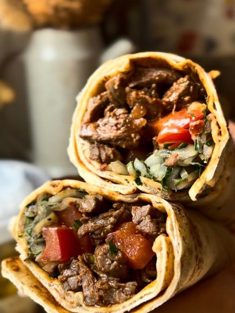 Beef tantuni in a lavash bread with tomatoes, onion and sumac, pickled peppers, parsley