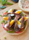 Pan Bagnat opened with tomato slices, green onion, radishes, eggs, tuna and anchovies, and lots of olive oil